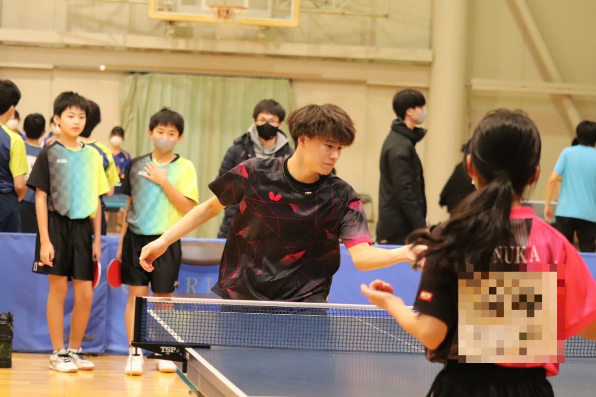 写真：加藤遼（北陸大学）と打ち合う中学生/提供：北陸大学卓球部